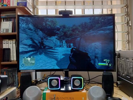 A photo of a computer monitor with a webcam on top, showing the game Crysis running on full screen.