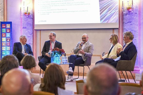 Bühne des Events mit den Teilnehmenden an der Podiumsdiskussion 

Dr. Frank Mentrup, Oberbürgermeister der Stadt Karlsruhe
Johannes Arnold, Oberbürgermeister der Stadt Ettlingen
Prof. Peter Schäfer, Leiter der Abteilung “Industrie, Innovation, wirtschaftsnahe Forschung und Digitalisierung”, Ministerium für Wirtschaft, Arbeit und Tourismus Baden-Württemberg
Jürgen Moßgraber, Abteilungsleiter Informationsmanagement und Leittechnik, Fraunhofer IOSB
 Britta Wirtz, Geschäftsführerin, Messe Karlsruhe
