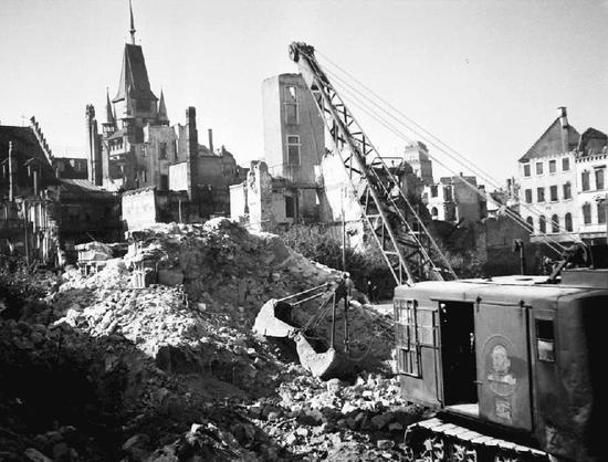 Kriegsschäden in Freiburg im Jahr 1945. Ein Bagger arbeitet in den Trümmern.