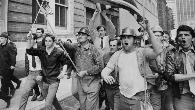 White male construction workers, in hard hats, carrying U.S. flags, rampage through New York.