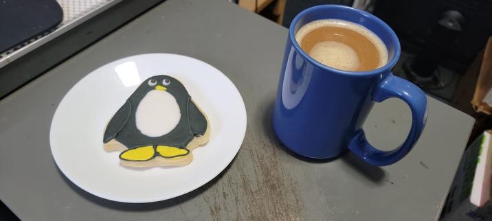 Penguin shaped & decorated cookie, with a mug of Coffee.
