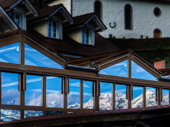 Schneeberge spiegeln sich in grossen Fenstern eines Restaurants.