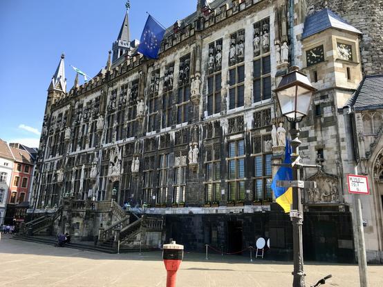 Fassade des Aachener Rathauses, an dem mittig über dem Portal die Europa-Flagge weht.