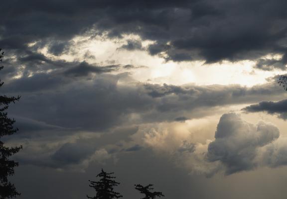 Dramatic dark clouds fill the sky with patches of light peeking through, creating a moody and atmospheric scene.