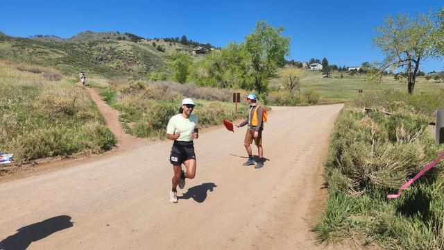 A man in a bright green shirt wearing number 267 crossing a dirt road.