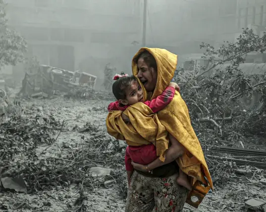 A woman holding a child in a grey lifeless landscape,