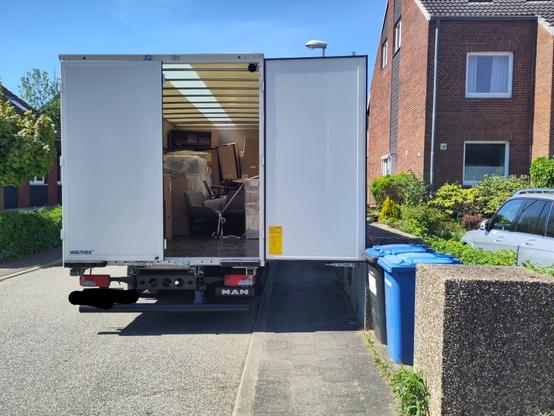 Ein Lkw mit Kofferaufbau von hinten. Der Lkw parkt zwar auf der Straße, aber durch die offen stehende rechte Tür des Kofferaufbaus wird der Gehweg über seine ganze (ohnehin sehr schmale) Breite versperrt.