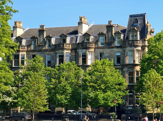 A French Renaissance style late Victorian tenement rising above the trees of Queen's Park in Glasgow.