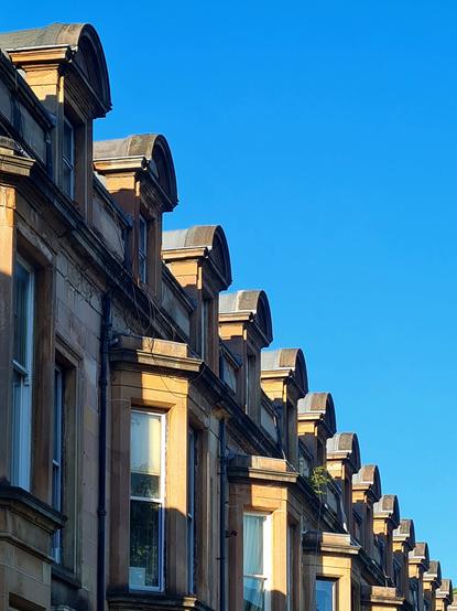 A repeated series of pedimented dormer windows against a clear blue sky.