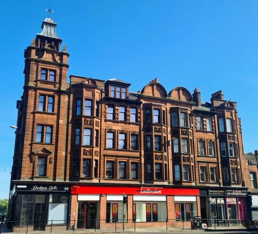 An ornate red sandstone Glasgow tenement with a distinctive square corner tower.