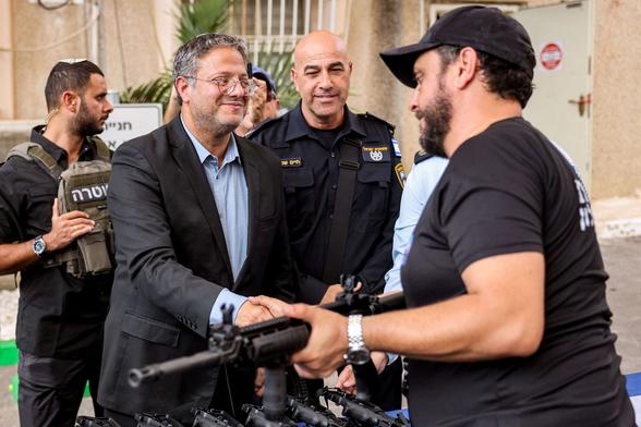 Israel's National Security Minister Itamar Ben-Gvir (center) shakes hands with a volunteer of the new civilian guard unit while handing out M5 automatic assault rifles, during the unit's inauguration ceremony in the southern city of Ashkelon on October 27, 2023.