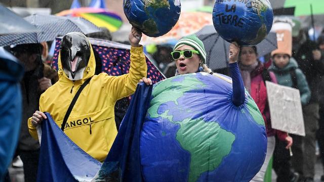 Des manifestants sont déguisés en planète Terre et en animal.