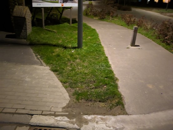 The left side of the image shows the existing paving stones of the sidewalk stopping at an angle (just following the properly line in front of them).
Then a section of grass in between, varying between 0,5 and 1 m.
And then on the right is a cyclepath coming onto the road perpendicular to the main road.  