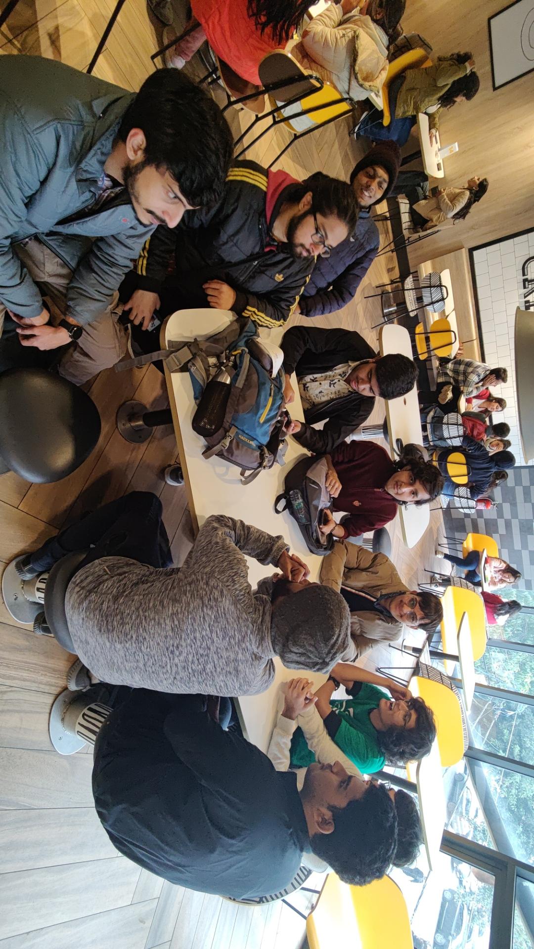 10 young men sitting around a table at a McDonald's and conversing animatedly.