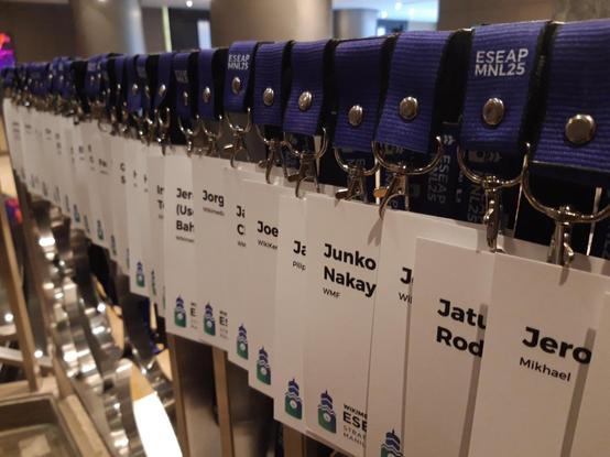 Photo of many lanyards and badges in a line hanging on a railing
