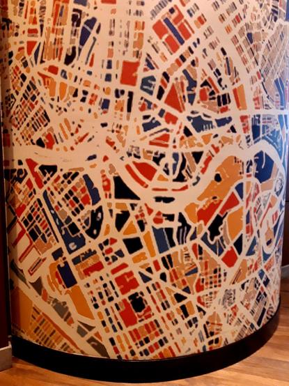 Wallpaper on a curved wall featuring a map of central Manila with streets and rivers in white and city blocks in various random colors