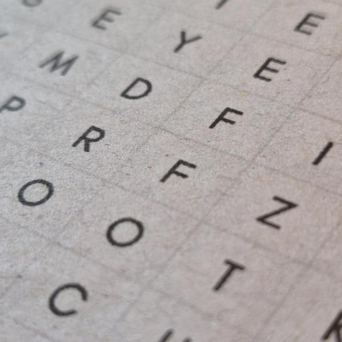Macro shot of a grid of letters a la word search printed on paper.