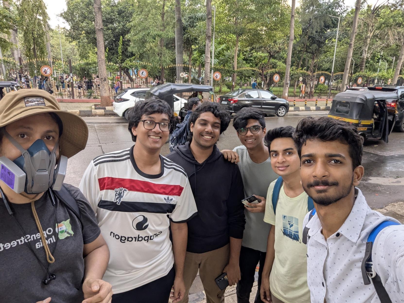 A selfie of 6 men smiling at the camera. Behind them is a busy road and Chembur's Diamond Park. A selfie of 6 men smiling at the camera. Behind them is a busy road and Chembur's Diamond Park.