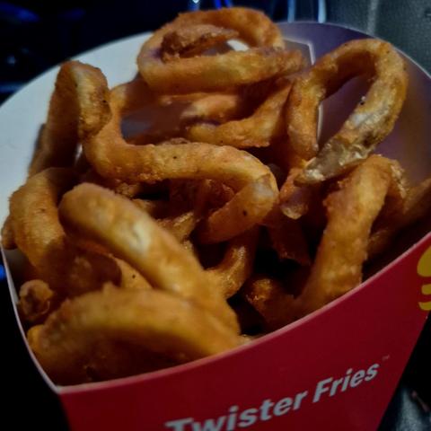 Close-up photo of a packet of McDonald’s Twister Fries; the fries are curved instead of straight and they are coated in an orange glaze