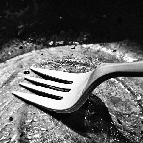 Sharp black and white macro photo of a fork in a bowl with harsh highlights and shadows