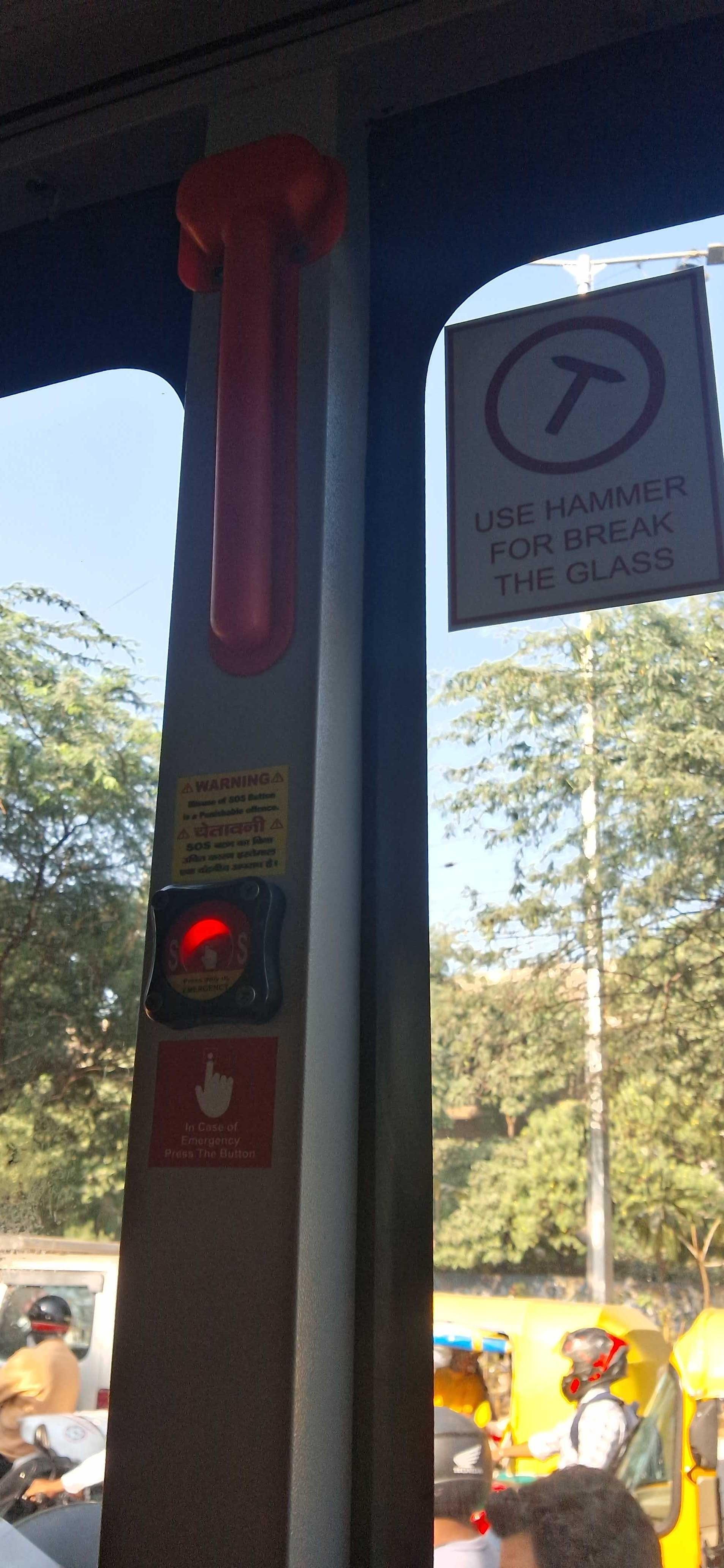 A hammer for breaking glass during emergency which is wrapped in a red plastic cover in a bus