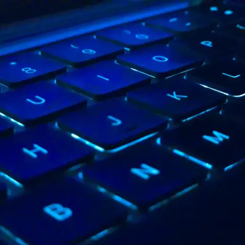 Dark blue-tinted macro photo of a backlit keyboard depicting the following keys: 8, 9, 0, -, U, I, O, P, H, J, K, L, B, N, and M