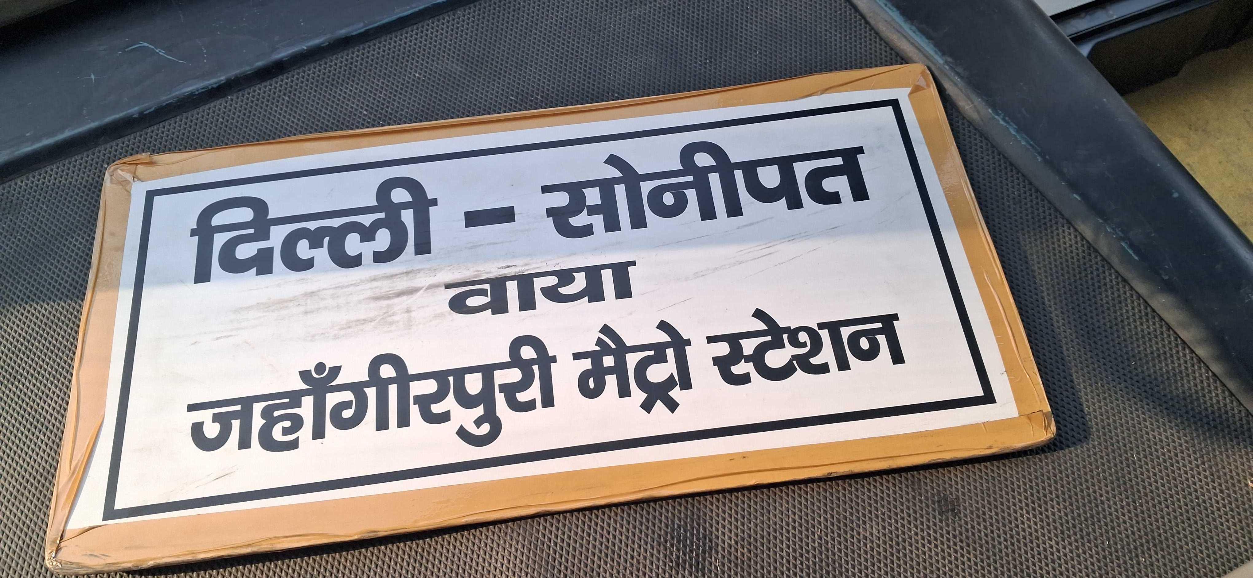 एक बड़ा सा बोर्ड जिसपे "दिल्ली-सोनीपत वाया जहांगीरपुरी मैट्रो स्टेशन" लिखा हुआ है