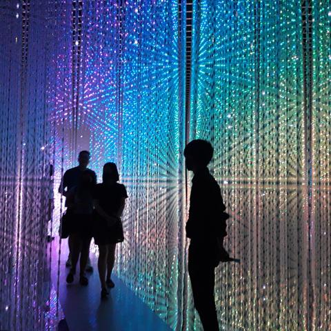 Rainbow-colored matrix light installation with the silhouettes of five people