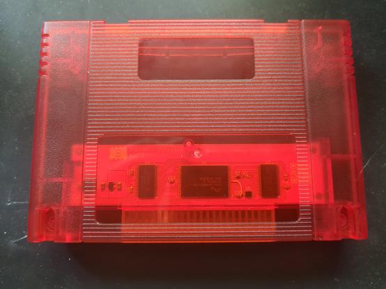 Photograph of a translucent red SNES cartridge case with the XiROM cart PCB inside. Seen from the back side.