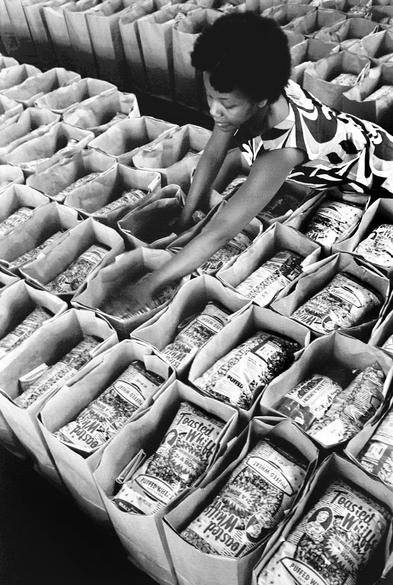 "Earlene Coleman, Black Panther Party member prepares bags of food for distribution at the Laney College student center for the Black Panther Community Survival Conference at the Oakland Coliseum where the Panthers gave away 6,000 bags of groceries."