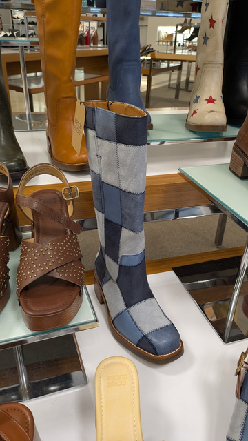 Photo of a display at a store showing a few different boots, including one made to look like it's made from patches of leather dyed to look like different colors of denim
