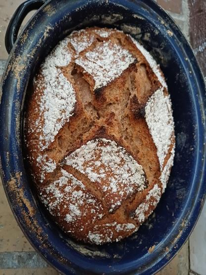 Ein tief eingerissenes Brot in einer emaillierten Auflaufform.