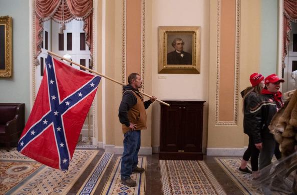 A person stands inside Capitol while holding Confederate Flag. Otherwise known as the filthy rag