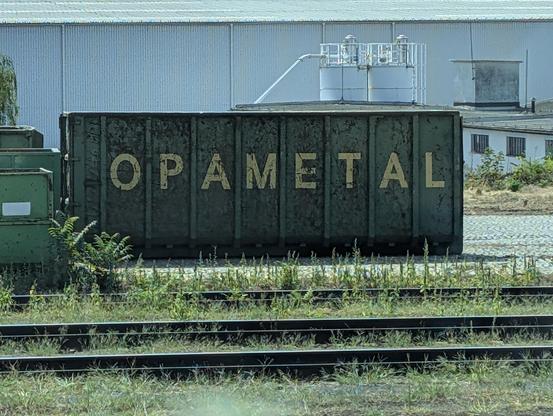 Foto eines großen Frachtcontainers auf einem Bahnhof, auf seiner Seitenwand steht groß "OPAMETAL".