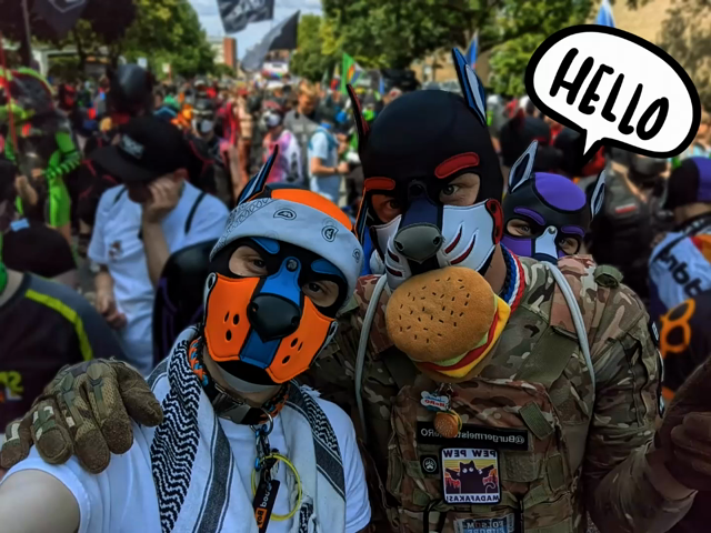 An animation:
First frame: Aki and HeRO taking a selfie in the Hamburg Pride parade. 

Second frame:
Same scene but Nad is poking out his head behind HeRO with a speech bubble saying hello
