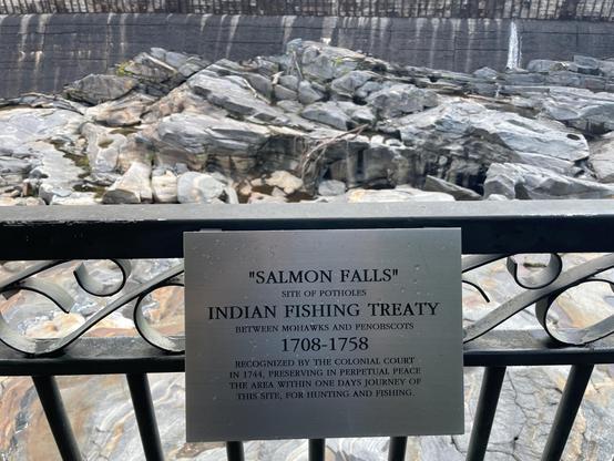 A metal sign on the view point railing above the potholed stretch of exposed riverbed. 

"SALMON FALLS"
SITE OF POTHOLES
INDIAN FISHING TREATY
BETWEEN MOHAWKS AND PENOBSCOTS
1708-1758
RECOGNIZED BY THE COLONIAL COURT IN 1744, PRESERVING IN PERPETUAL PEACE THE AREA WITHIN ONE DAYS JOURNEY OF THIS SITE, FOR HUNTING AND FISHING.