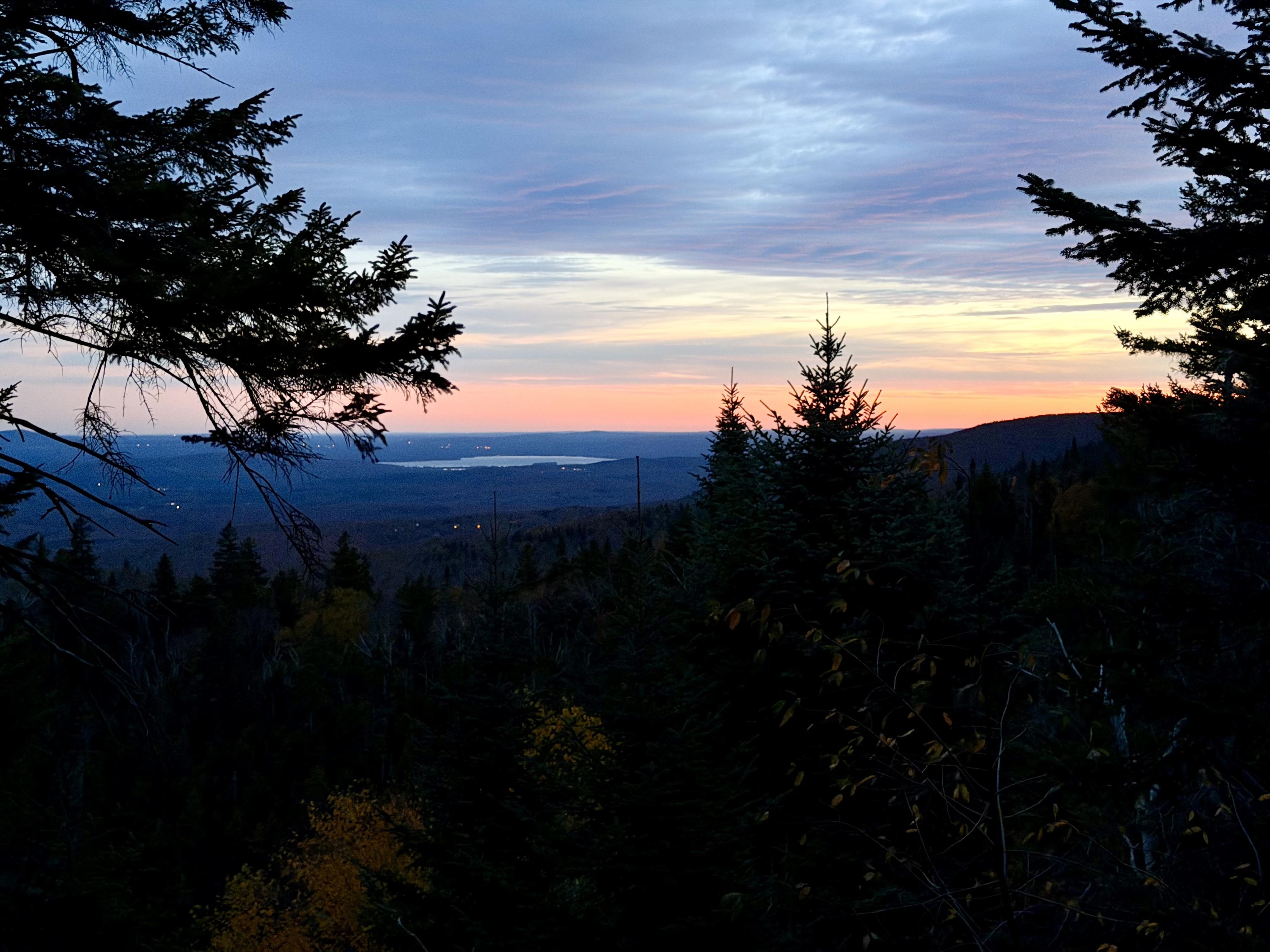 Lever de soleil du sommet avec des couleurs rougeoyantes et des arbres en premier plan.