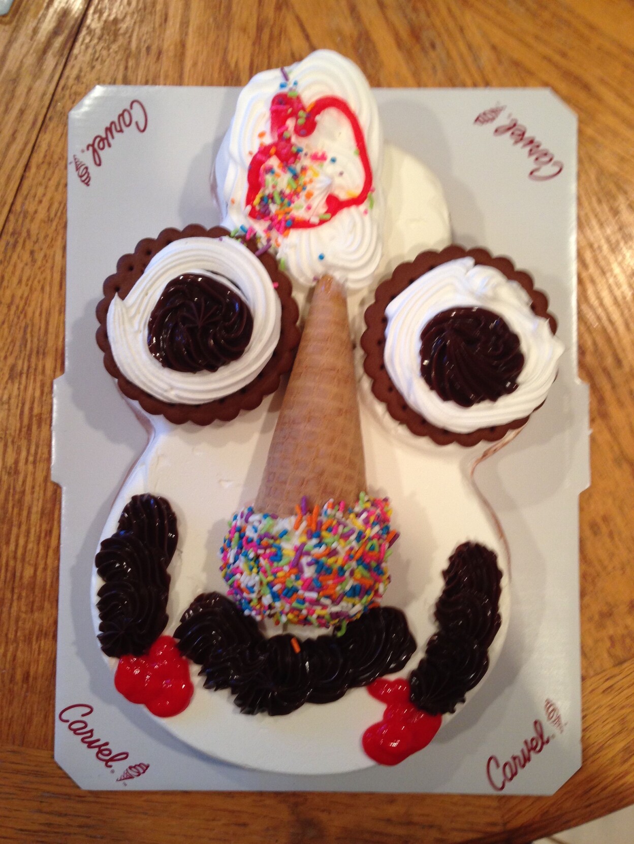 Carvel ice cream cake shaped like a head. Eyes look like cupcakes, nose is an ice cream cone (with ice cream and sprinkles) and odd icing mouth.