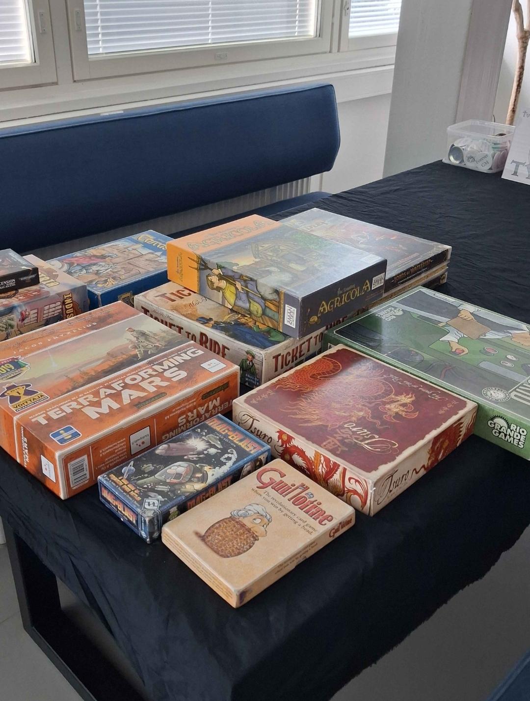 Kuvassa Tyrmän lautapelipisteen pelejä pöydällä. A picture from Tyrmä boardgame station, with a punch of games on the table.