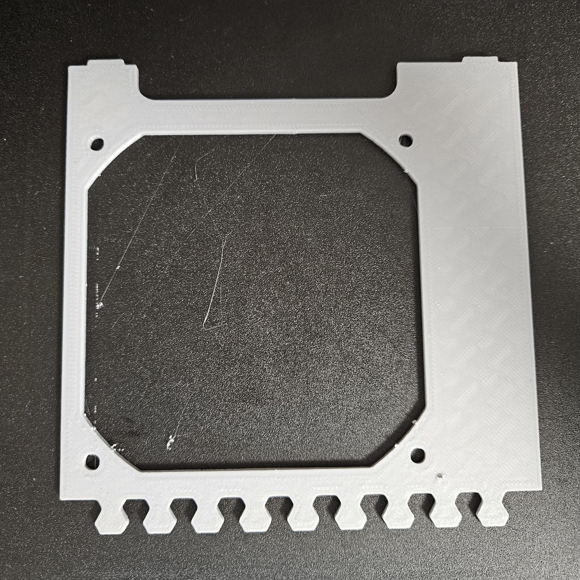 A light grey panel with a fan mount and an interlocking pattern along one edge. The infilling pattern is faintly recognisable from the surface.
