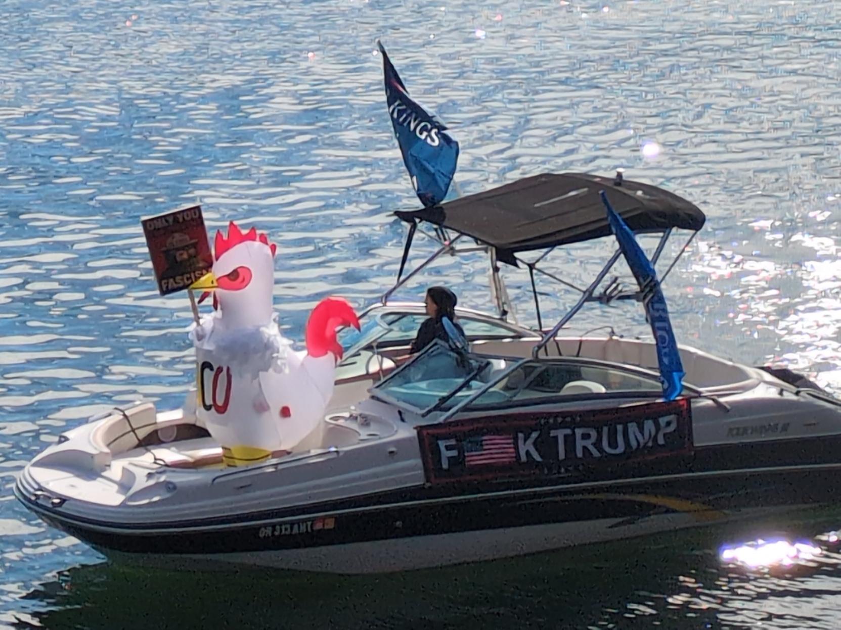 TACO chicken inflatable on a boat with anti Trump banners and flags