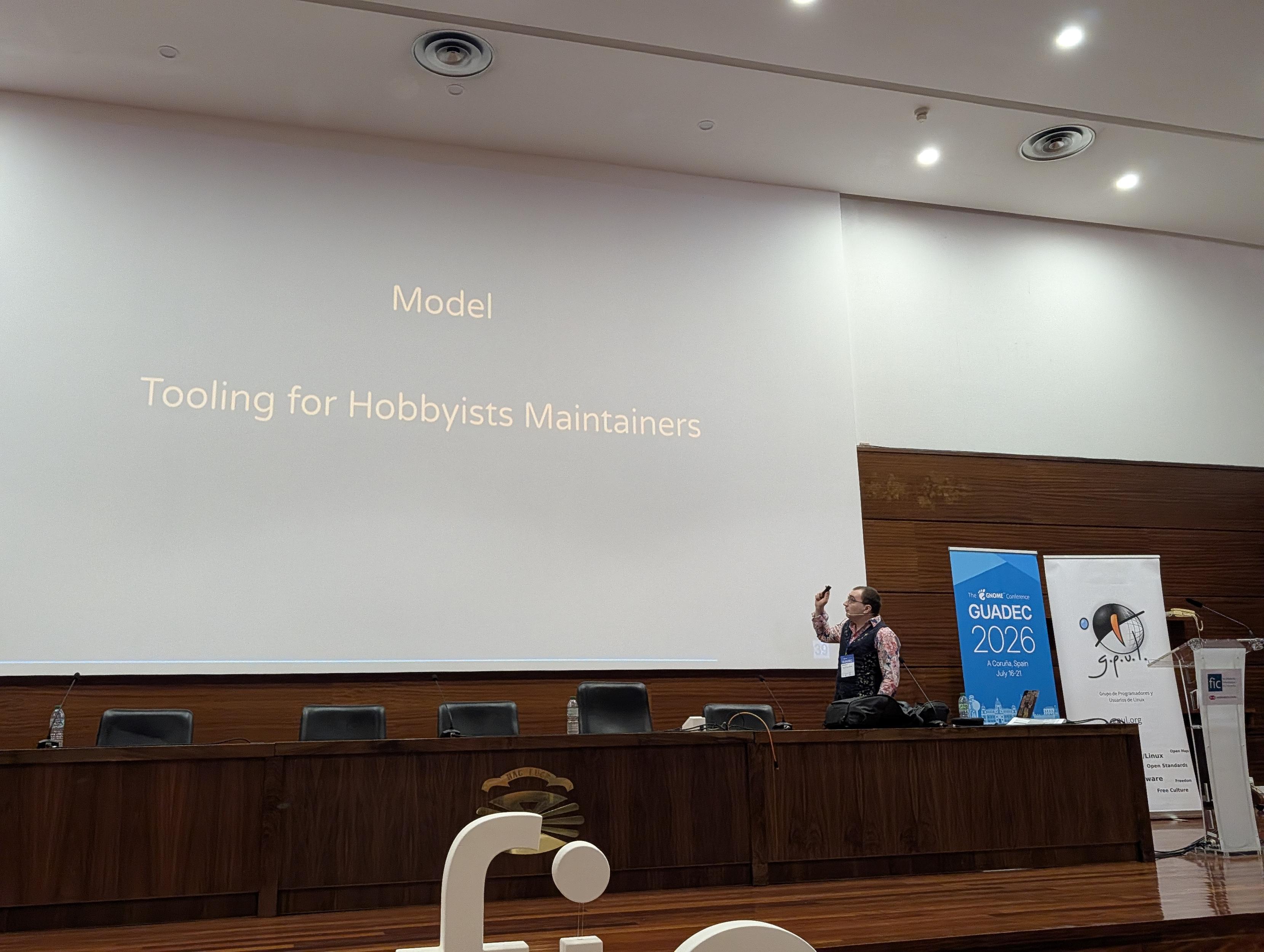 Thomas in front of a a slide that says "Model: Tooling for hobbyist maintainers"