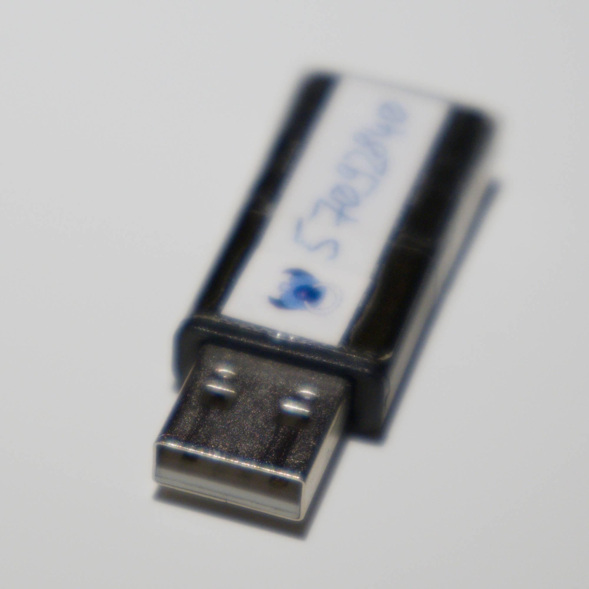 A USB device with a scotch-taped label. The label shows the Gnuk logo, and the handwritten logical identifier of the device.

The device is an ST-LINK V2 clone. The programmer's connector has been removed.