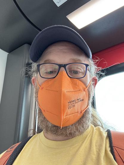 Selfie, middle aged man with bright orange ffp2 mask, glasses and blue base cap wearing a yellow tshirt