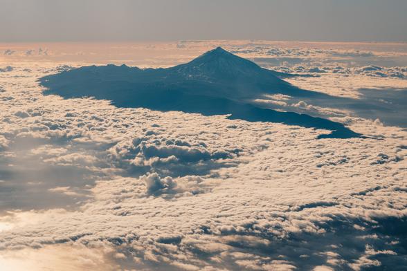 Teide volcano covered by clouds, seen from an airplane.