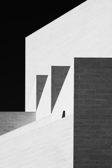 A monochrome photo of a building with different shapes formed by light and shadow.