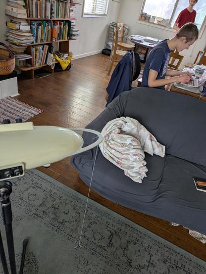 a string hanging off a Theremini (not important 🙈) that's been drawn plumb by a random toy key tied on the end so it can swing. an older teenager is working some calculations on a laptop while a slightly younger one awaits the results