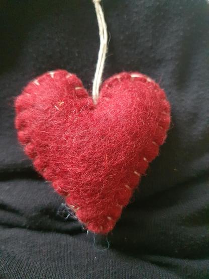 small red heart made from wool on black fabric