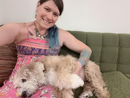 Selfie with my dog Luna, a shaggy cream and white cockapoo, lying with her head on my lap. We’re sitting on an old avocado green couch. Luna has her paw up a little bit, to entice me to rub her belly. I’m wearing a big smile, because this makes me so happy.