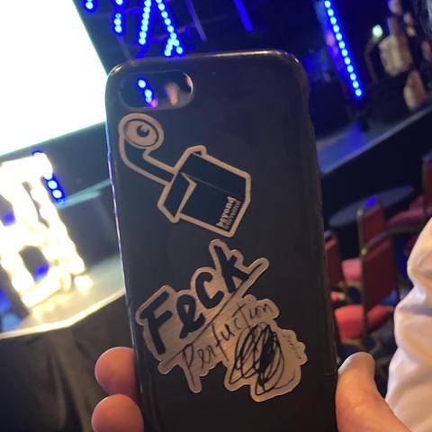 Blick durch die handyhülle auf die bûhne mit dancing tobi. auf der hülle ein btconf logo und ein geckperfuction sticke